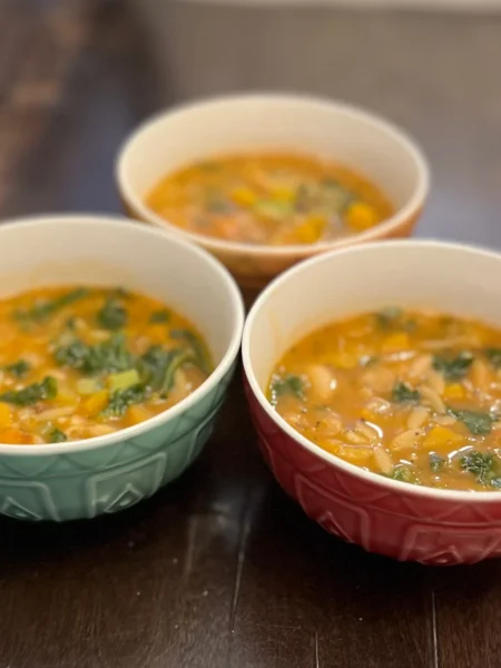 Three bowls of colorful minestrone soup